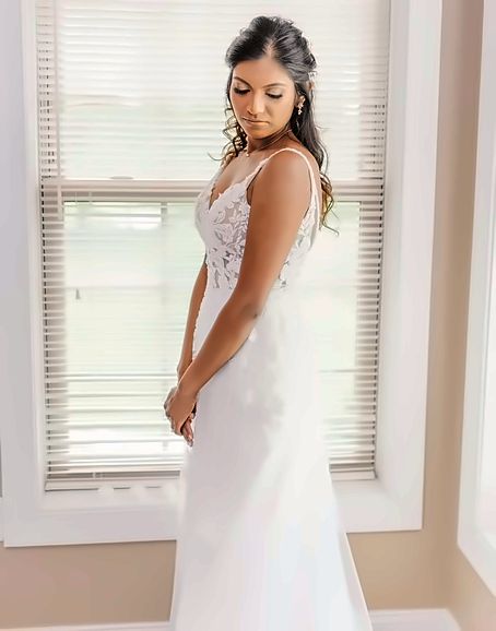 Bride in a lace gown by a sunlit window, natural bridal makeup