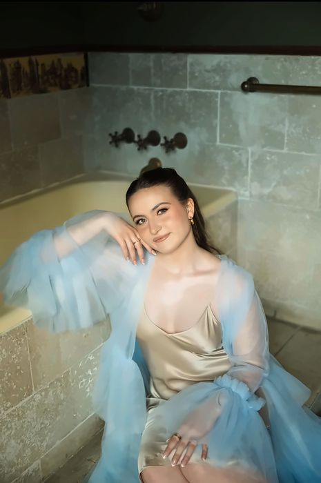 Woman in a champagne slip and blue robe in a vintage bathtub, photoshoot makeup